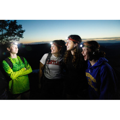Students wearing head lamps on an evening hike