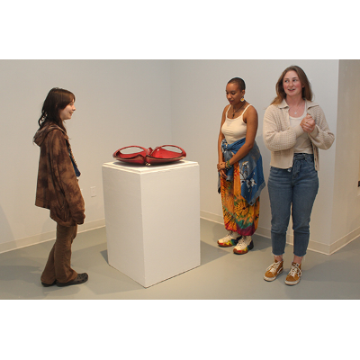 Three students view and discuss a piece by Errol Willett.