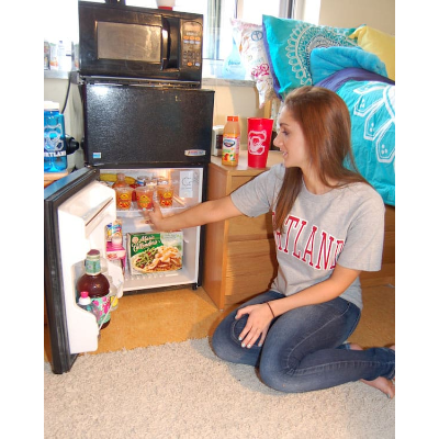 Student looking in her mini refrigerator in her room in her residence hall
