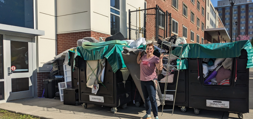 Student standing in front of bins of items collected for donation to the Cortland ReUse center
