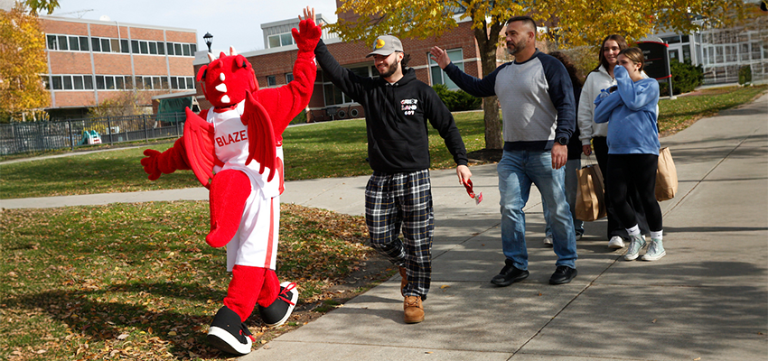 blaze giving a high five to a prospective student and parent