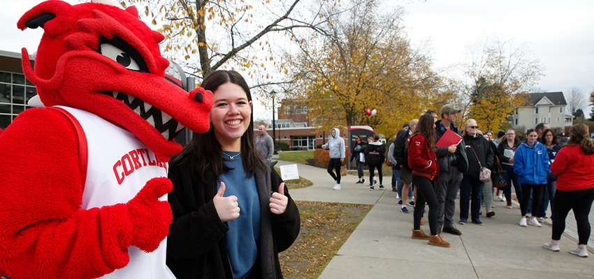 Blaze poses with prospective student on campus during open house. A tour is being led behind them.