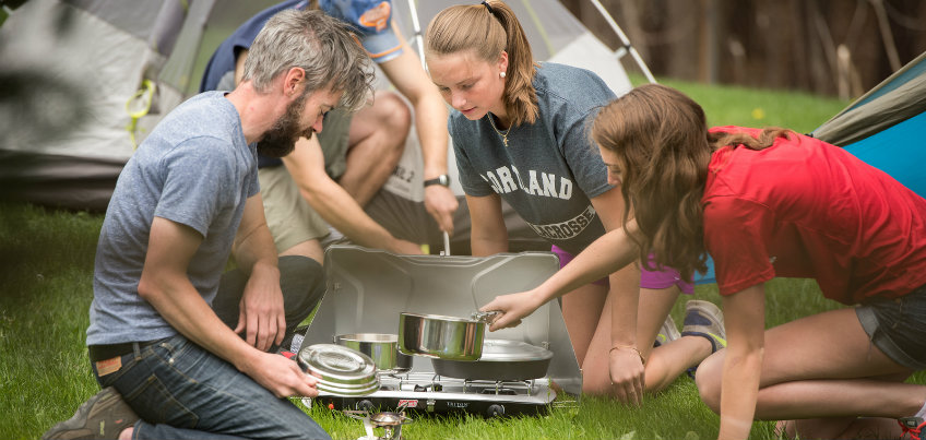 Students using outdoor stove rental while camping in tents