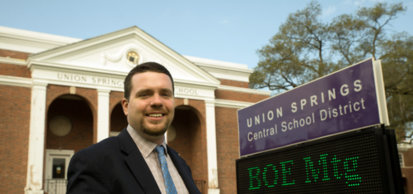 Educational Leadership alum Jarett Powers standing in front of district office in Union Springs