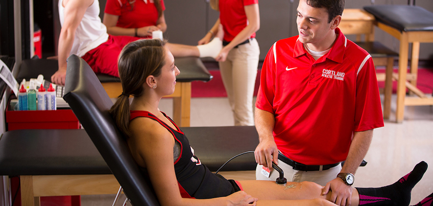 Athletic training student getting clinical experience treating a leg injury