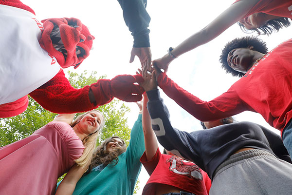 Students join hands with Blaze the Red Dragon Mascot.