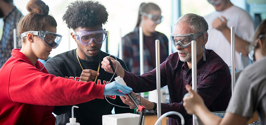 Students working with a professor in a chemistry lab