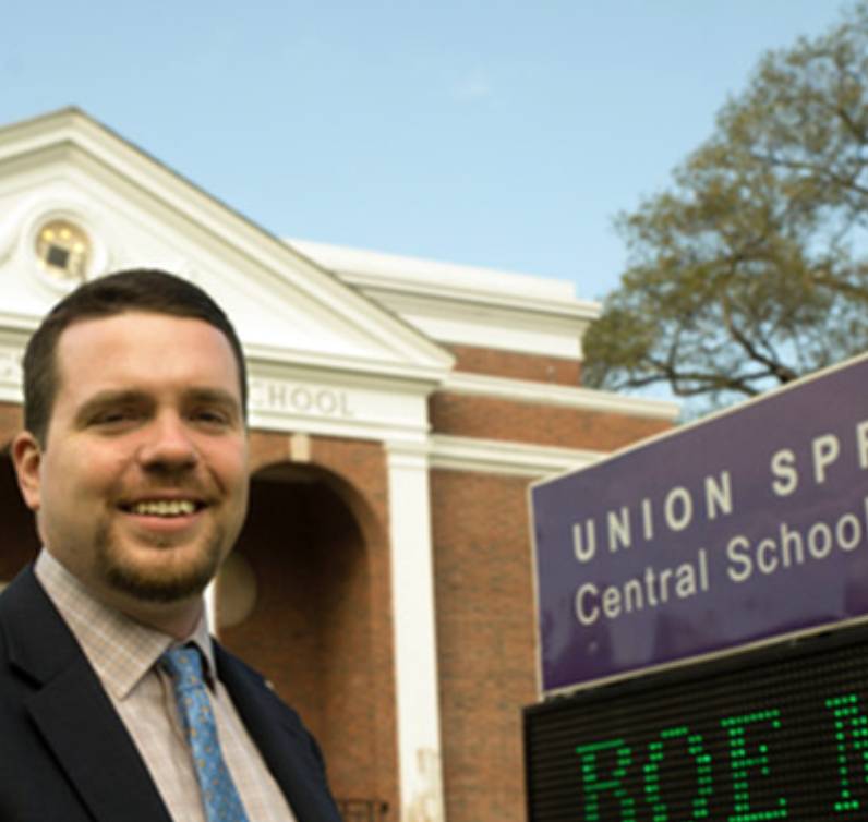 School leader standing in front of school building