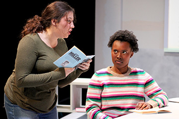 Student reading out loud from a book on stage