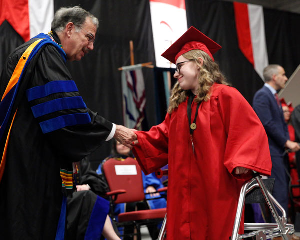 Student using a walker shaking hands with President Bitterbaum